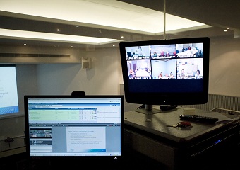 Picture of two computer screens showing people watching the presentation via videoconferencing. 